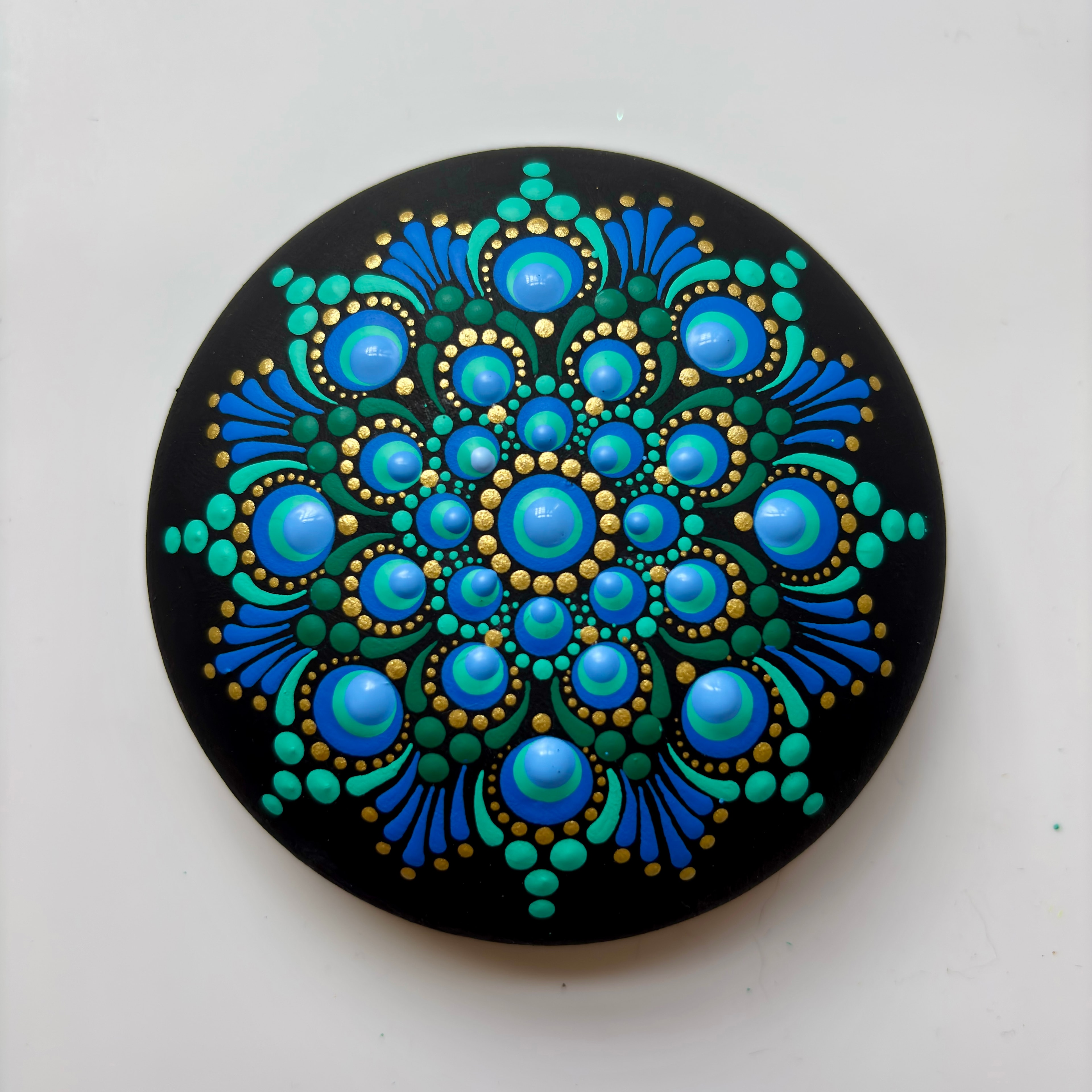 Blue and teal mandala dot painting with gold accents on black background
