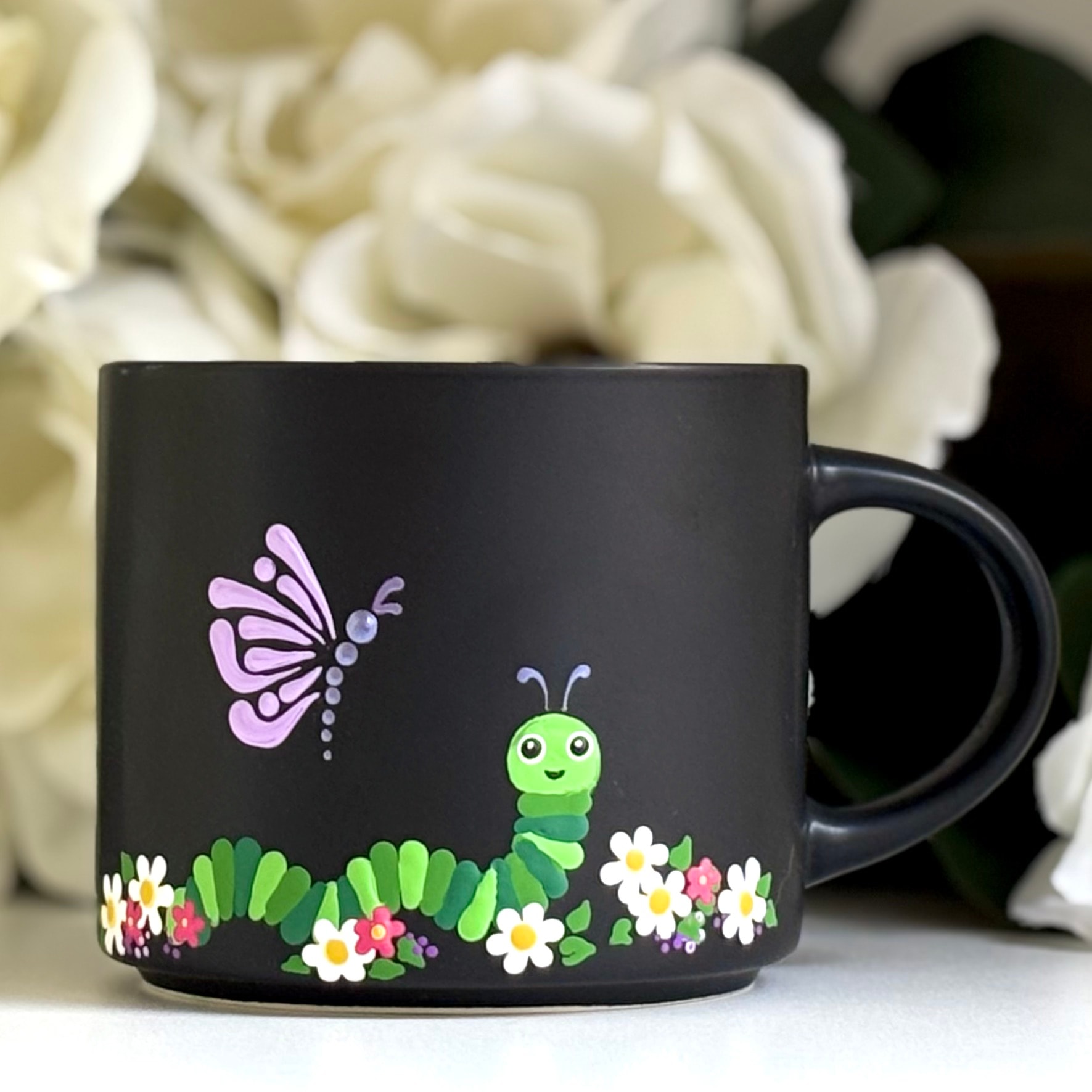 Black mug with hand painted butterfly caterpillar and floral design